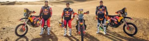 Toby Price, Matthias Walkner und Kevin Benavides neben ihren KTM Rallye-Motorrädern in der Wüste, bereit für die Dakar Rally 2024.