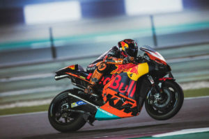Ein KTM-Rennmotorrad in voller Fahrt auf der Rennstrecke mit einem Fahrer in voller Montur.